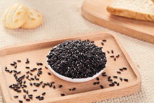Displaying a bowl of black rice kept in a wooden tray.