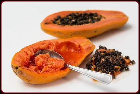 2 half sliced papayas one with seeds and other one with seeds removed