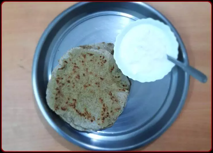 2 Bajra roti and a bowl of curd in a steel plate.